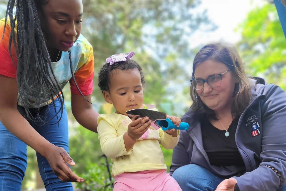child and 2 teachers gardening