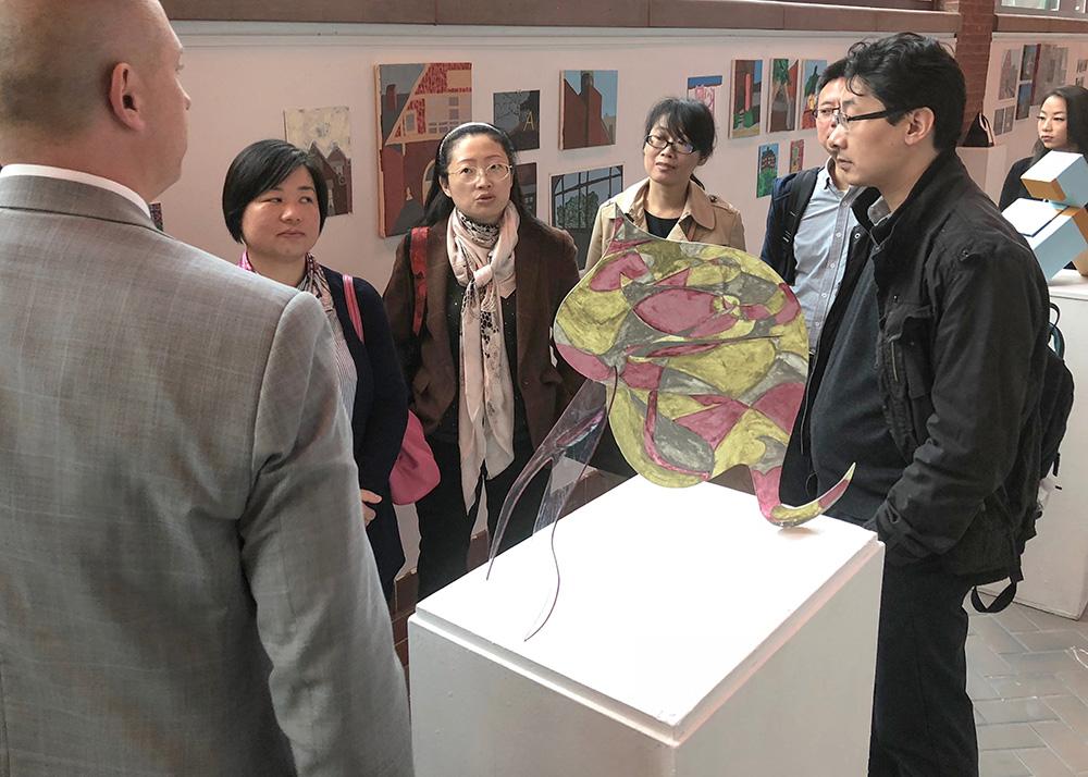 Multiple Visiting Scholars  team members look through the various pieces on display in an art gallery.