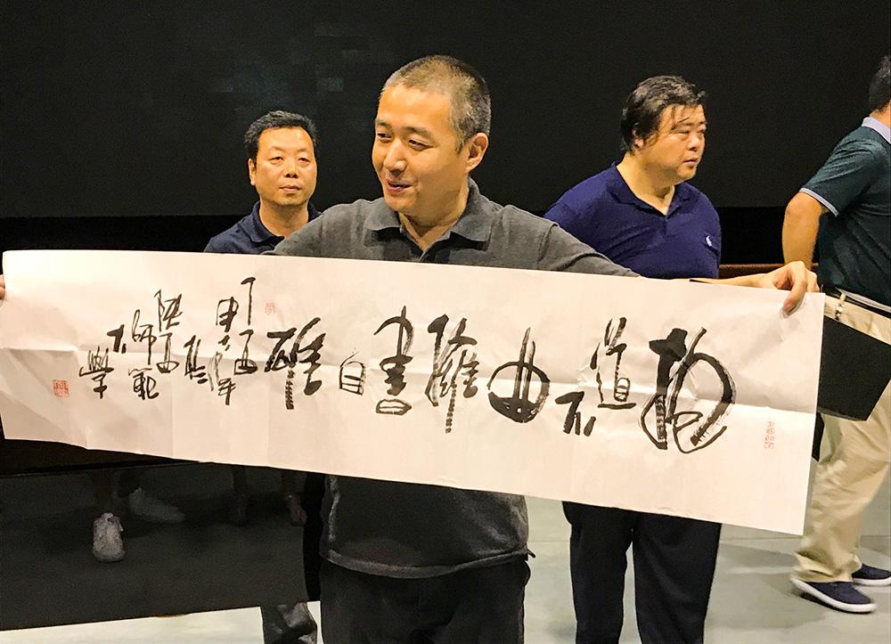Visiting Scholars hold up a wide piece of paper with Chinese characters.