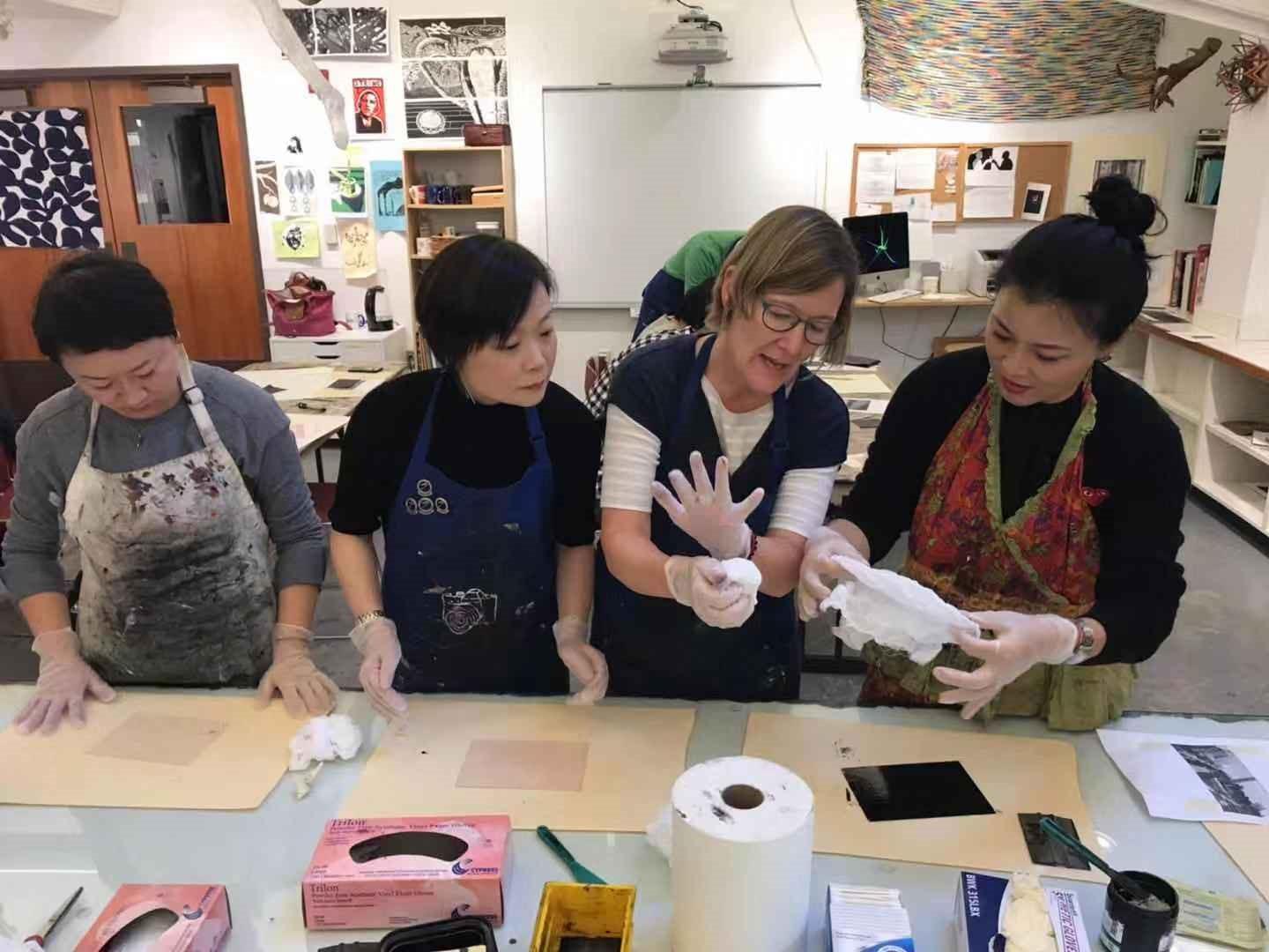 The Visiting Scholars team wears paint-stained aprons as they work on art project at ECA school.