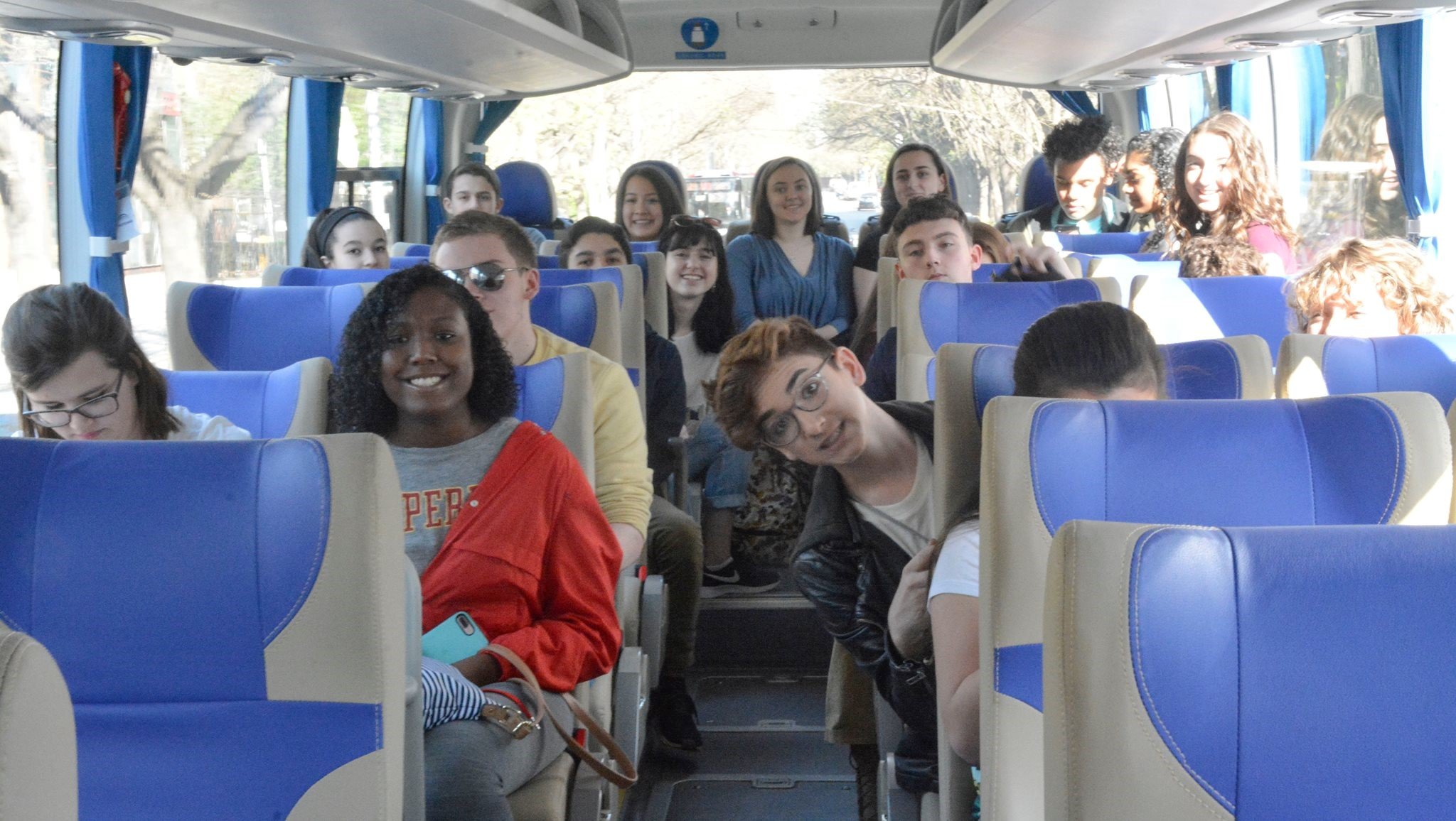 	A group of students smile for a group picture on a tour bus.